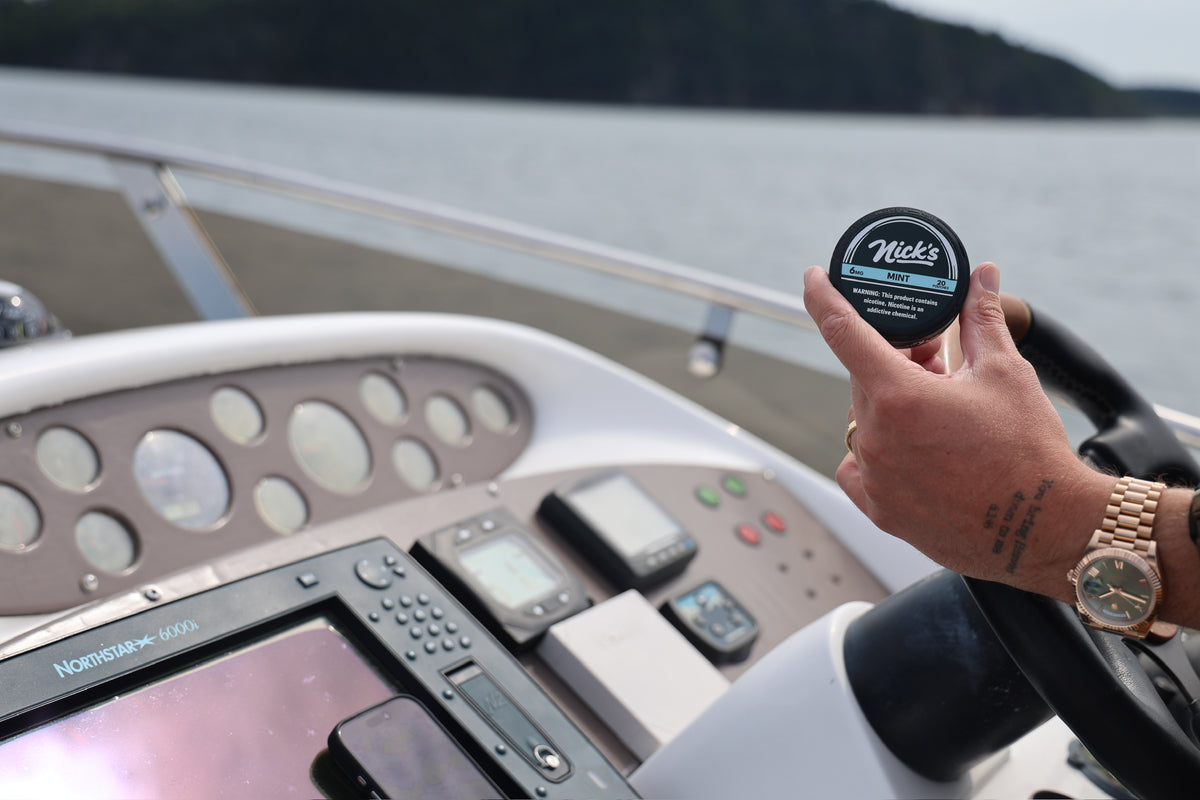 Mason holding a can of Nick's Mint at the helm of a boat